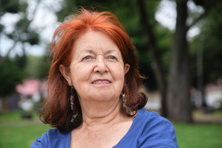 Portrait of a confident mature woman smiling and looking slightly upward in a positive attitude, outdoors.の写真素材