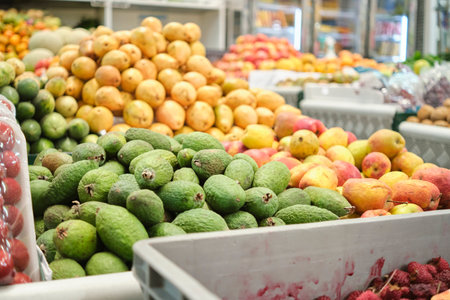 Piles of feijoas, apples and guavas in the fruit section of a market.の写真素材