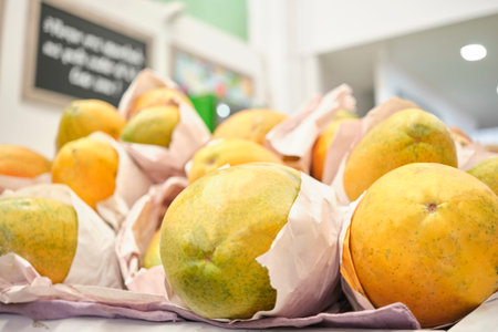 Ripe papayas for sale at a fruit and vegetable market stall.