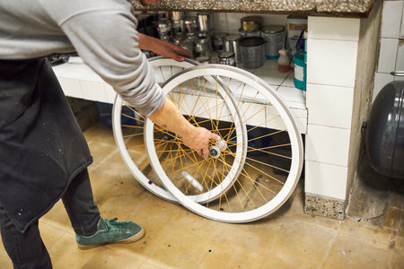Unrecognizable bicycle mechanic fitting two bike rims in his repair shop.の写真素材
