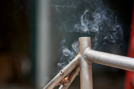 Smoking metal, manual bicycle renovation work, paint removal process using a torch fire to change the color of a bike frame. Close up view, no people.の写真素材