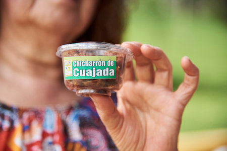 Aratoca, Santander, Colombia, Nov 23, 2022: unrecognizable woman holding a cup of chicharron de...