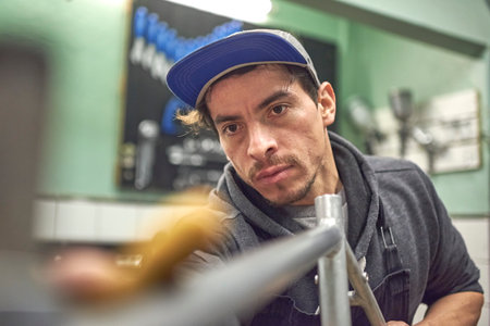 Portrait of a young Hispanic bicycle technician working in his workshop. Composition with selective focus.の写真素材