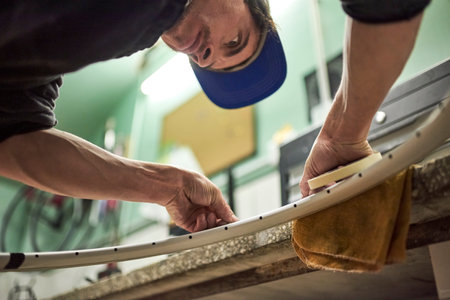 Latin man preparing a bicycle wheel to paint in his workshop. Low angle view composition.