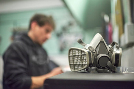 Protective mask for painting in a work environment, in the background is seen, out of focus, a male...
