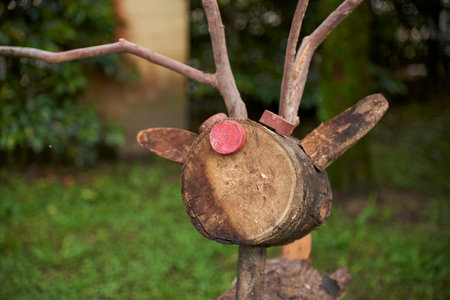 Portrait of a wooden Christmas reindeer, Rudolph, with its distinctive red nose, in a garden.の写真素材