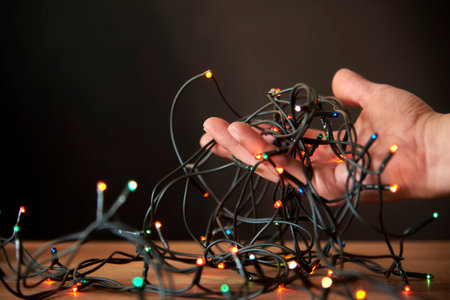 Christmas scene: young hand holding a string of colored lights. Composition with copy space.の写真素材