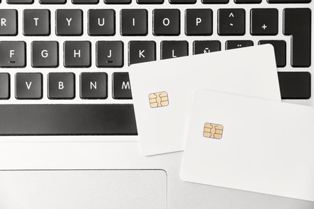 Pair of blank white credit or debit cards on a laptop keyboard. Top view. Concepts of plastic money and online shopping.の写真素材