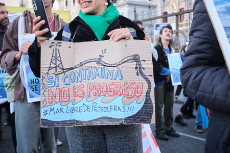 Buenos Aires, Argentina, Oct 5, 2023: protest against offshore oil exploitation. Woman with a phone and an environmental sign: If it pollutes, it is not progress. Be free of oil companies.のeditorial素材