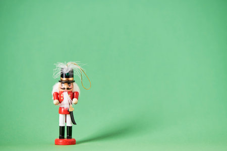 Traditional colorful wooden Christmas nutcracker in red suit with a green background, minimal composition with copy space.の写真素材