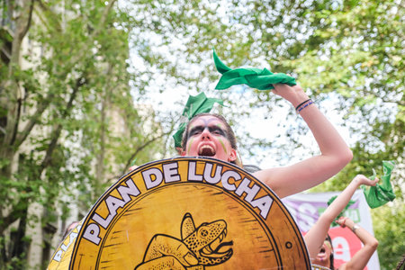 Buenos Aires, Argentina; March 8, 2024: Young woman shouting a feminist slogan waving a green scarf and holding a shield with the text Fight plan, during the international women strike.のeditorial素材