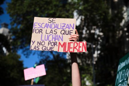 Buenos Aires, Argentina; March 8, 2024: International feminist strike. Hand raising a poster: They are scandalized by those who fight and not by those who die.のeditorial素材