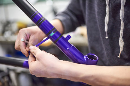 Unknown person working on a custom bike frame painting design in purple and black, a creative and...