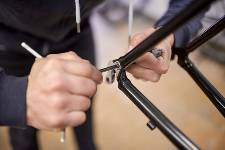 Unrecognizable man assembling a bicycle he is servicing in his bike shop. Real people at work. Close...