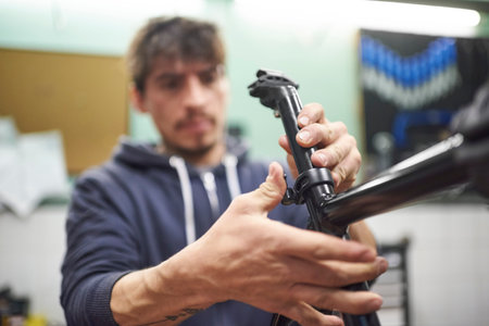 Young hispanic man assembling a bicycle in his bike workshop as part of a maintenance service. Real...