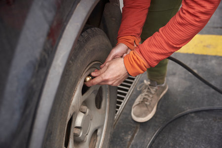 Unrecognizable person measuring the air in the tires of his vehicle at a service station.の写真素材