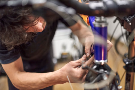 Repairman assembling the braking and shifting system of a bicycle as part of the maintenance service he performs in his shop. Real people at work.の写真素材