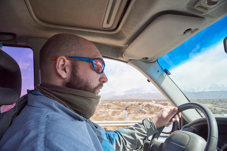 Side portrait of a young man traveling by car, concentrating on driving his vehicle. View from...