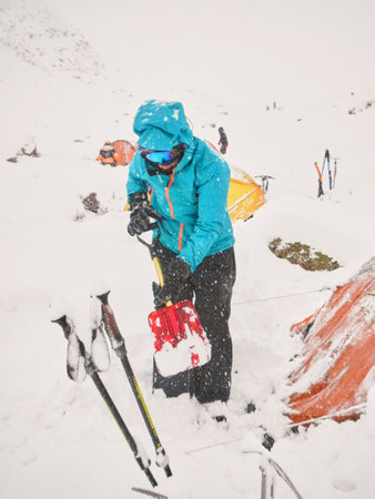 Woman mountaineer removes snow from above and around her tent during a snowfall using a shovel, in Mendoza, Argentina.の写真素材