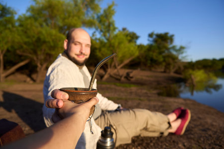 Smiling man drinking mate with someone. This Argentinian infusion is a symbol of sharing and...