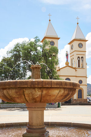 Main square of Sutamarchan, in Boyaca, Colombia: in the foreground a water fountain and in the background the Our Lady of Health Parish, the main Catholic temple of the town.の写真素材