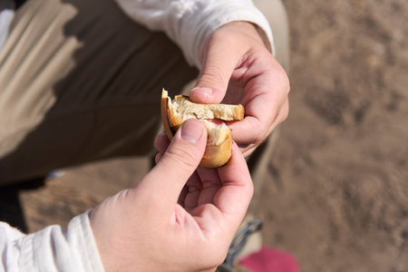 Hands of unrecognizable person eating toast bread outdoors, traveler eating breakfast a sunny...