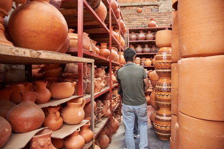 Unrecognizable man in a store filled with shelves of ceramic pots in Raquira, Boyaca, Colombia, a tourist town known for its craftsmanship and its pottery.の写真素材