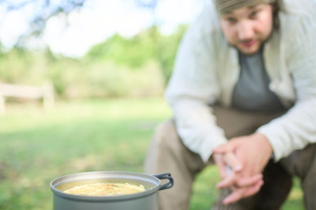 Male traveler waiting for his meal to be ready, rice with vegetables that he is cooking using a...