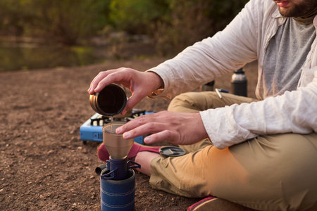 Coffee filtering process. Man making coffee for breakfast outdoors early in the morning by a creek, in El Palmar National Park, Entre Rios, Argentina.の写真素材