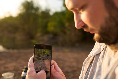 Traveler taking a photo at sunrise to share it on his social networks. Concept: use of technology connects us even in remote locations. El Palmar National Park, Entre Rios, Argentina.の写真素材