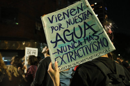 March 25, 2026; Buenos Aires, Argentina: protest against the amendment to the Glacier Law. Hand raising a poster: They are coming for our water. No more extractivism.のeditorial素材