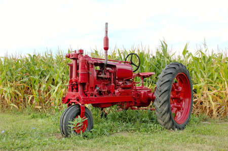 Antique red tractor in front of a corn field. Michigan, U.S.A.  12MP camera.の写真素材