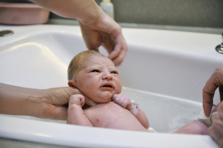 A nurse gives a newborn baby his first bath with dad helping. Model released.の写真素材