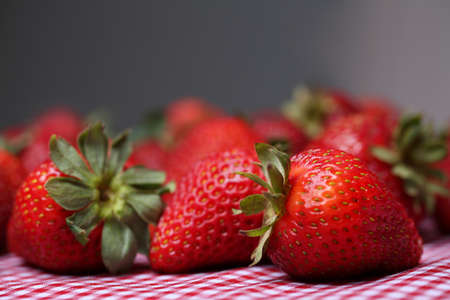Strawberries laying on a red gingham tableclothの写真素材