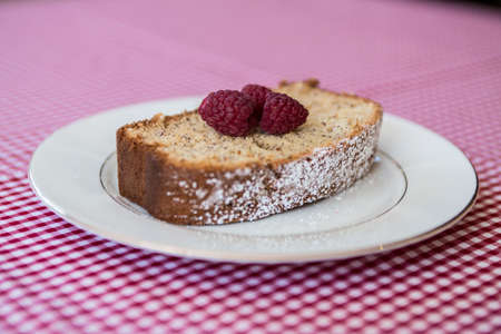 Banana bread with raspberries on a white plateの写真素材