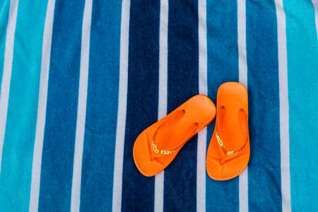 Orange flip flops on blue striped beach towelの写真素材