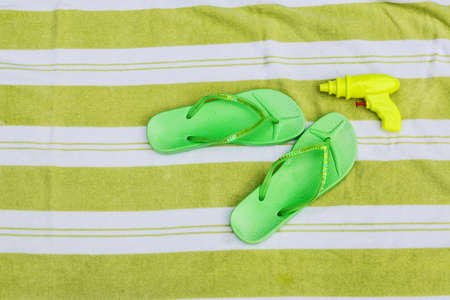 Green flip flops and squirt gun next to a poolの写真素材