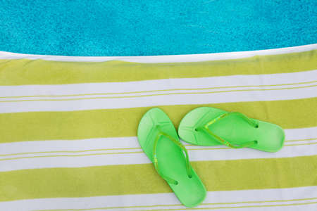 Flip flops on a striped towel next to a poolの写真素材