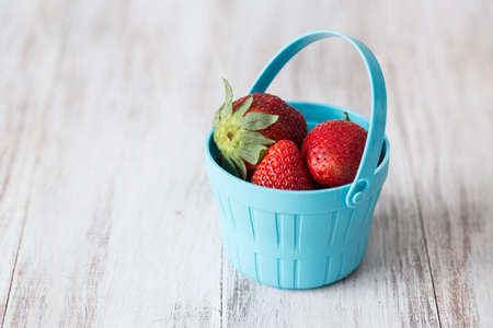 Strawberries in a blue plastic bucketの写真素材