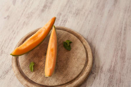 Cantaloupe slices on wood cutting board with mint leaves from aboveの写真素材