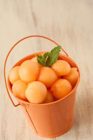 Cantaloupe balls in blue teacup with mint leafの写真素材