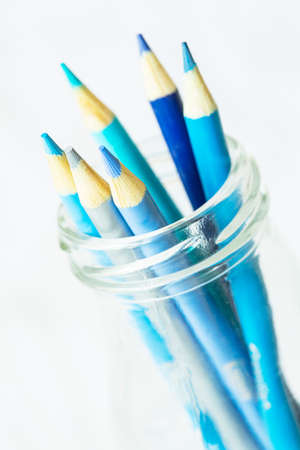 Pastel cool blue color pencils in glass jar on whiteの写真素材