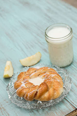 Danish bakery pastry with milk and fresh sliced apple on blue wood table verticalの写真素材