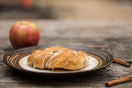 Danish pastry on wood table with apple and cinnamon sticksの写真素材