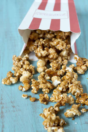 Bag of caramel popcorn spilling onto wood table close upの写真素材