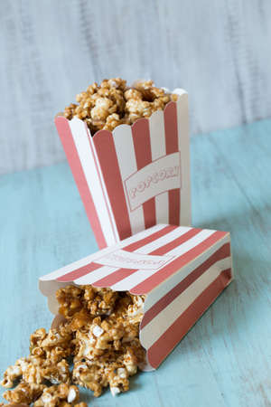 Caramel popcorn in bags with one spilling onto wood tableの写真素材