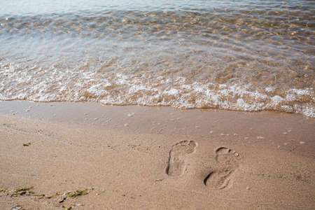 Footprints in the sand of beach on Lake Michigan with waveの写真素材