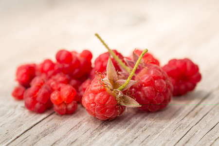 Red ripe raspberries on wood table close up
