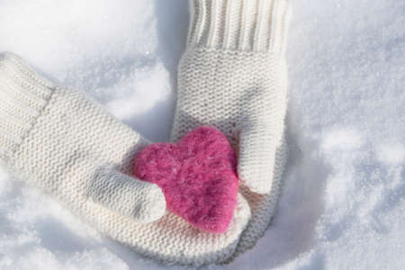 Mittens holding Valentines Day love heart in the snow in winterの写真素材