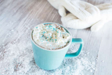 Close up mug of winter hot chocolate drink with mittens and snowの写真素材